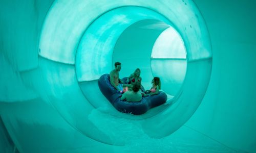 Besucher rutschen im Reifen durch eine Röhre