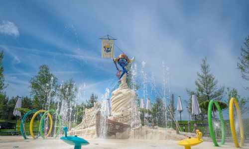 Snorri thront auf einer Sandburg im Rulantica Themenbereich Snorri Strand