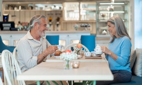 Ein älteres Ehepaar sitzt mit Kaffee an einem Tisch