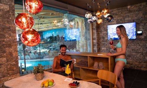 Eine Frau steht mit einem Cocktail in der Hygge Supreme Hydda, ein Mann sitzt nebendran am Tisch.