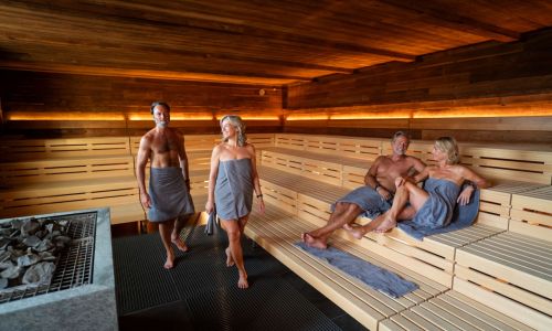 Zwei Senioren Paare sitzen in der Sauna in Rulantica Hyggedal