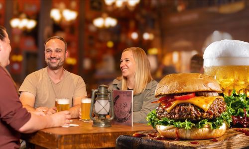 Drei Personen sitzen lachend an einem Tisch auf dem drei gefüllte Bierkrüge stehen. Im Vordergrund ist ein Burger und Bier abgebildet.