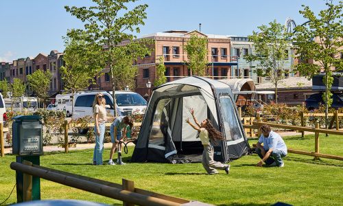 Eine Familie baut ihr Zelt auf einem Zeltplatz vom Europa-Park Camping auf. Im Hintergrund erkennt man Silver Lake City.