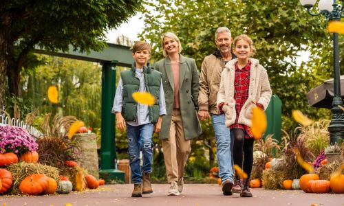 Een gezin van vier wandelt door het Duits themagebied van Europa-Park, dat sfeervol is aangekleed in herfststijl.